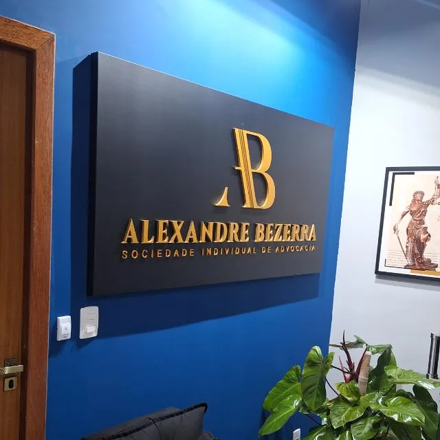 Placa do escritório Alexandre Bezerra – Sociedade Individual de Advocacia, em letras douradas sobre fundo preto, na parede azul da recepção